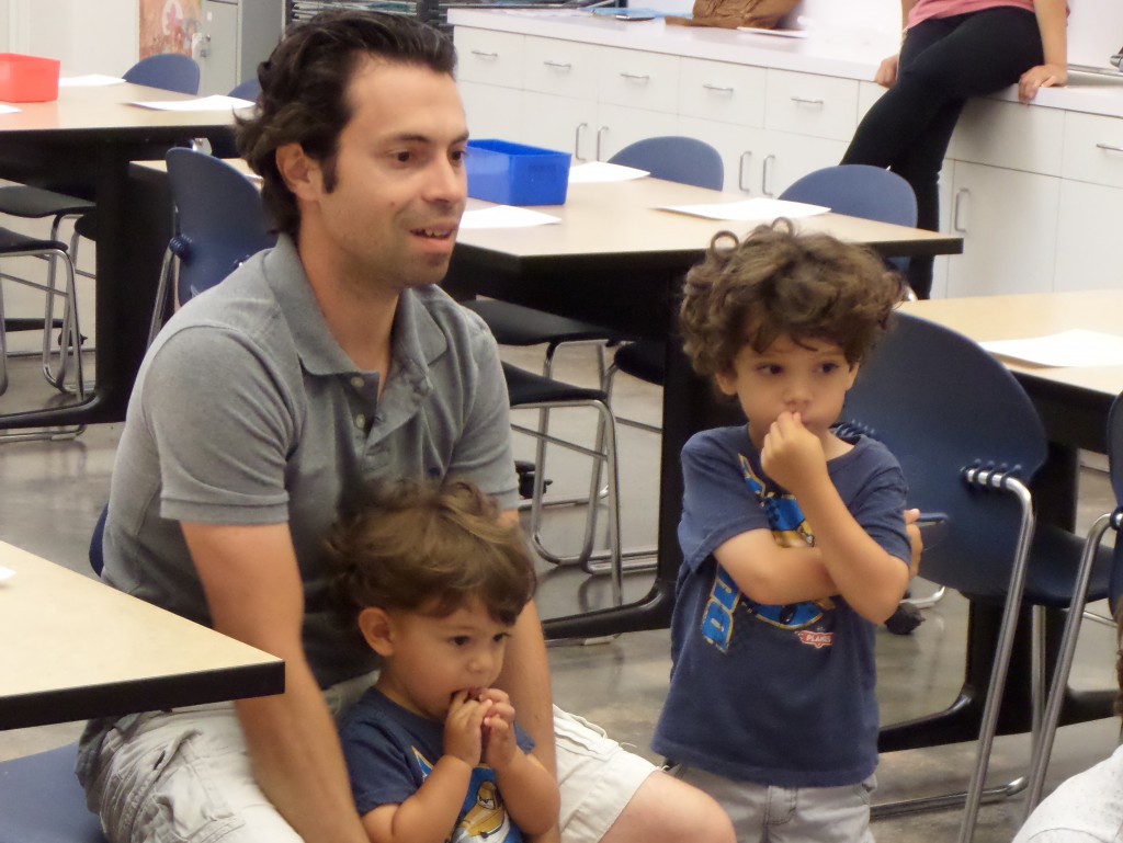 PHOTO BY TEAGAN HALBROOKS Ilya Kozadayev sits while his sons listen to story time during Art Adventures. He said usually his wife brings their sons. "They love art and it is a great way to expose them," he said.