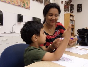 PHOTO BY TEAGAN HALBROOKS Akhila Vendula helps her son learn to color during the June 17 Art Adventures at the Fred Jones Jr. Museum of Art. She said he likes to be kept busy and she wanted him to have something to do while school is out. "I want him to see other kids, socialize and look at art too," she said.