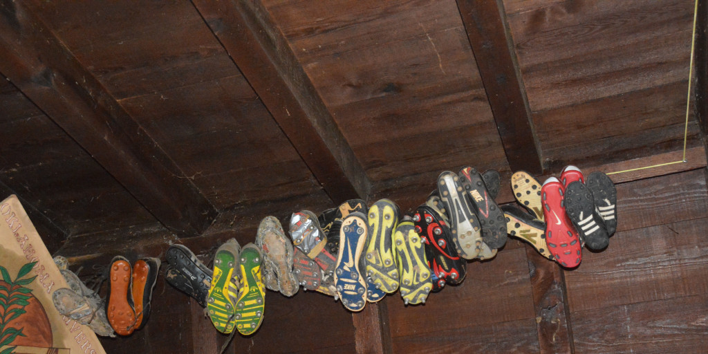 The boots hanging from the rafters of the OU rugby clubhouse belonged to players who have since died. Each shoe contains some of the person’s ashes. PHOTO BY: J.D. Baker   